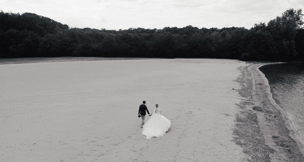 Brautpaar läuft am Strand richtung Horizont